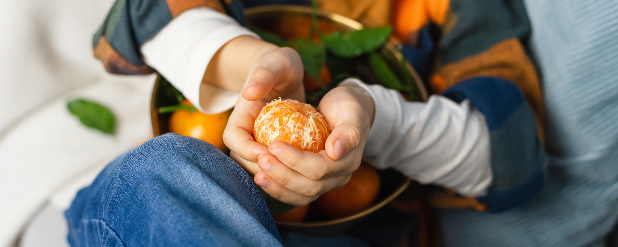 Child holding peeling clementine in hands