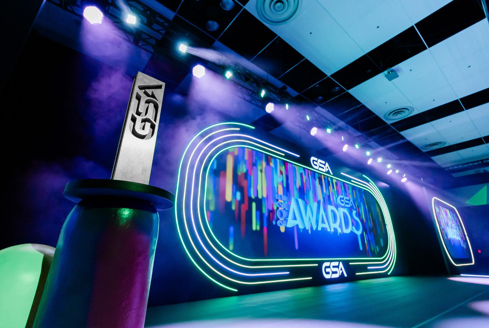 Event stage with the 2025 GSA Awards Celebration branding on a video screen next to an award trophy