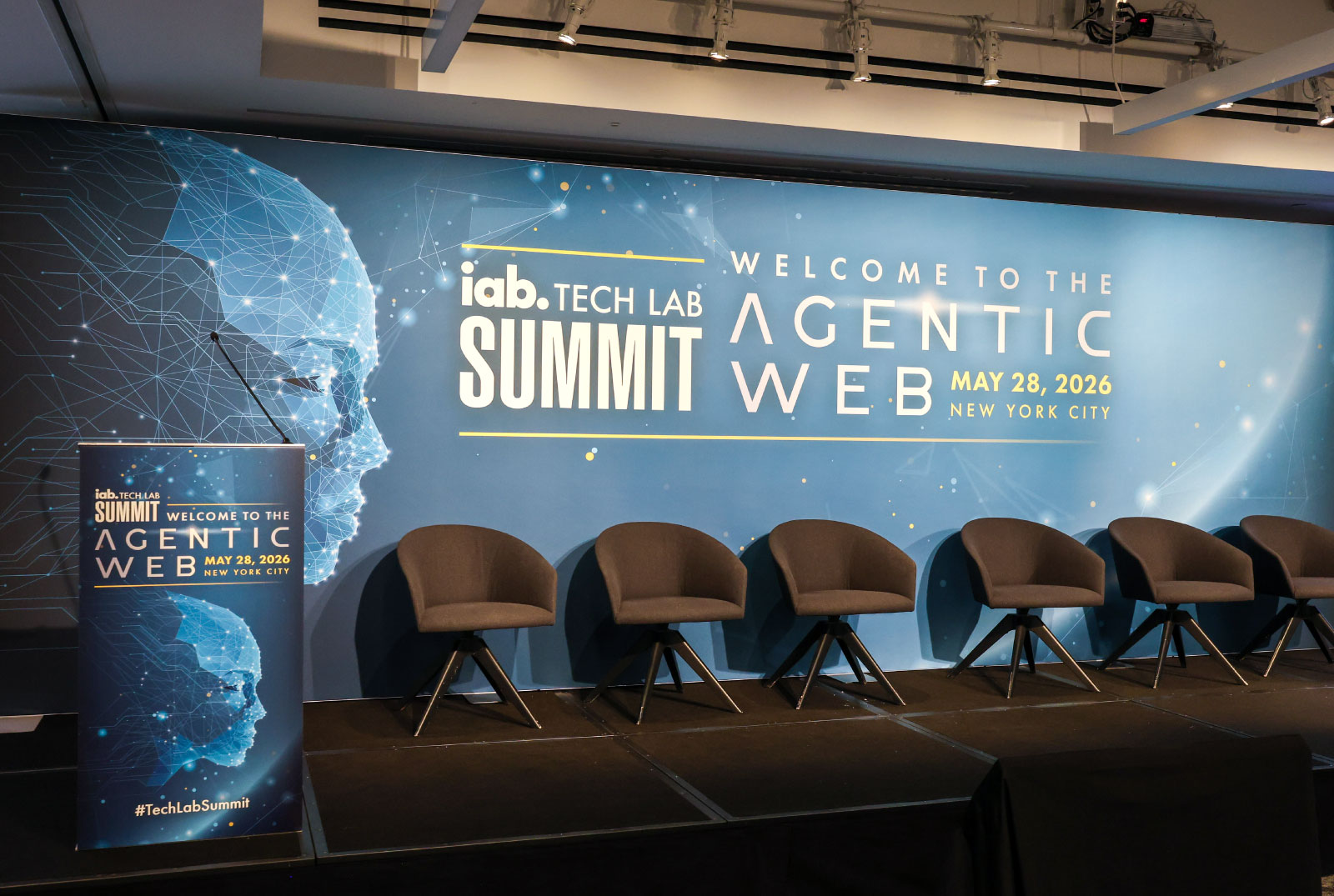 Auditorium containing chairs and a backdrop with IAB Tech Lab Summit Agentic Web branding